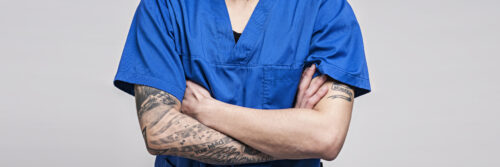 Auf dem Bild ist ein junger Pfleger mit Tattoos zu sehen